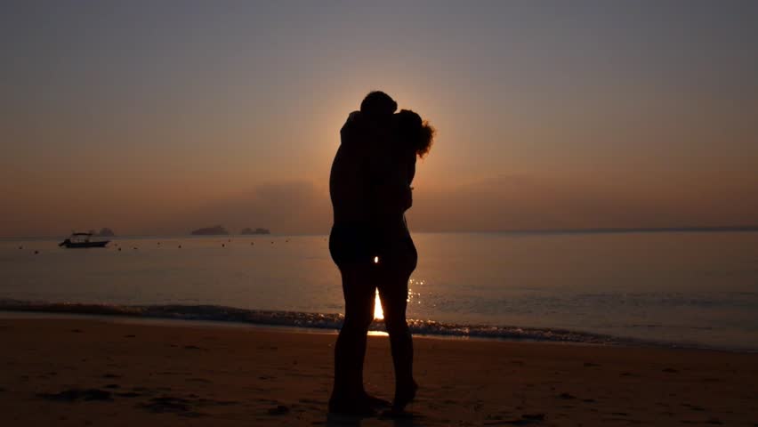 Silhouette Of Happy Couple Embracing On Beach At Sunset. Slow Motion ...